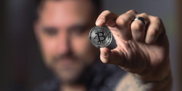 person holding silver bitcoin coin
